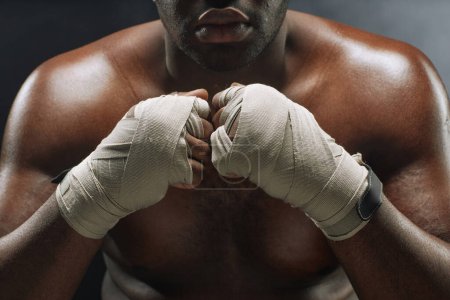 Téléchargez les photos : Gros plan dramatique du combattant afro-américain avec les mains enveloppées dans des bandages - en image libre de droit
