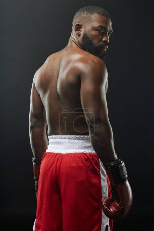 Foto de Vista posterior vertical del musculoso boxeador afroamericano posando sin camisa y usando guantes de boxeo - Imagen libre de derechos