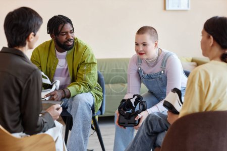 Foto de Grupo de jóvenes conversando con psicólogos mientras prueban gafas VR en la sesión - Imagen libre de derechos