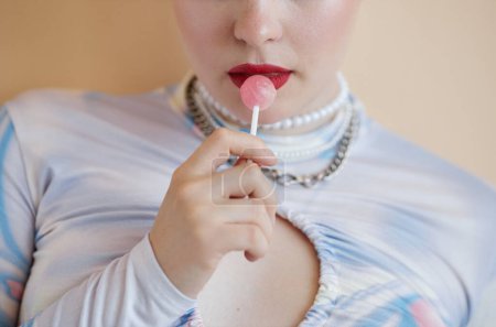 Foto de Primer plano de chica con lápiz labial rojo sosteniendo bonbon aislado sobre fondo claro - Imagen libre de derechos