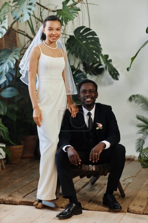 Téléchargez les photos : Portrait de mariage pleine longueur de jeune couple noir comme mariée et marié posant ensemble dans l'orangerie - en image libre de droit