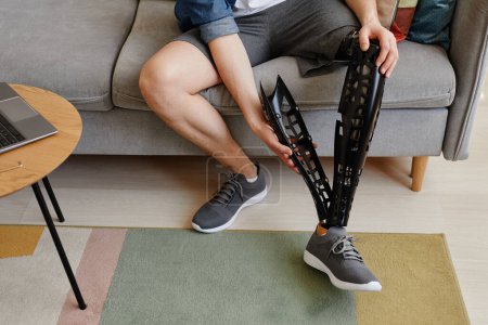 Téléchargez les photos : Vue de dessus gros plan de l'homme méconnaissable mettant sur la jambe prothétique à la maison, espace de copie - en image libre de droit
