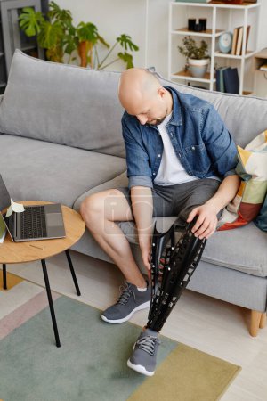 Téléchargez les photos : Portrait vertical complet de l'homme adulte portant une prothèse de jambe à la maison - en image libre de droit