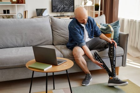 Téléchargez les photos : Portrait complet d'un homme adulte chauve portant une prothèse de jambe à la maison, espace de copie - en image libre de droit