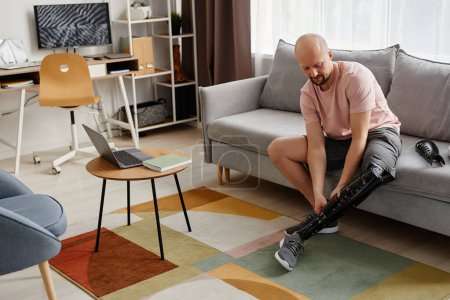 Téléchargez les photos : Portrait complet de l'homme handicapé assemblant la jambe prothétique à la maison, espace de copie - en image libre de droit