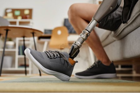 Téléchargez les photos : Gros plan d'un homme méconnaissable avec une jambe prothétique bionique à la maison à l'intérieur, espace de copie - en image libre de droit