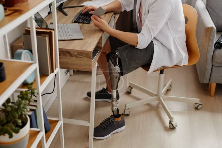 Closeup of adult man with prosthetic leg working from home and using credit card online, copy space
