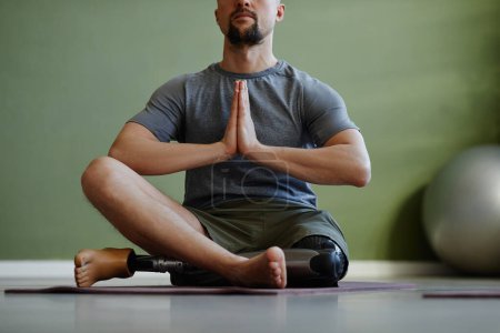 Photo for Adult man with disability enjoying yoga workout indoors and meditating sitting in lotus position - Royalty Free Image