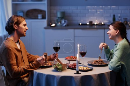 Foto de Retrato de vista lateral de pareja joven bebiendo vino mientras celebran aniversario en casa juntos - Imagen libre de derechos