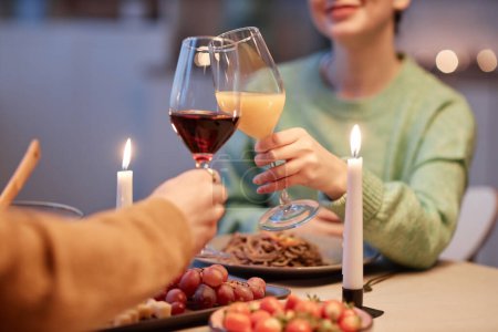 Foto de Primer plano de pareja joven bebiendo vino y disfrutando de una cena romántica en casa - Imagen libre de derechos