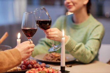 Foto de Primer plano de pareja joven bebiendo vino y brindando disfrutando de una cena romántica en casa - Imagen libre de derechos