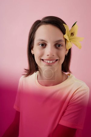 Foto de Retrato vertical de una adolescente sonriente con parálisis cerebral mirando a la cámara sobre fondo rosa en el estudio - Imagen libre de derechos