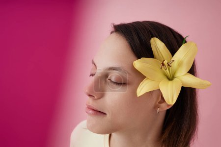 Foto de Primer plano retrato de hermosa adolescente con parálisis cerebral y flor en el pelo sobre fondo rosa, espacio de copia - Imagen libre de derechos