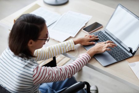 Foto de Vista de ángulo alto de la chica adolescente con discapacidad utilizando el ordenador en casa mientras estudia en línea, espacio de copia - Imagen libre de derechos