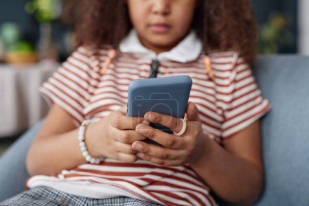 Foto de Primer plano de la joven chica negra sosteniendo el teléfono inteligente en las manos y navegar por Internet o jugar al espacio de copia del juego móvil - Imagen libre de derechos