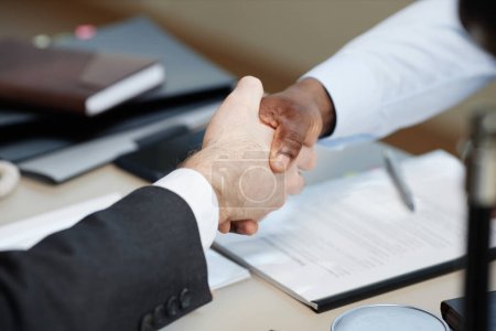 Foto de Primer plano de dos personas de negocios que dan la mano sobre la mesa en la oficina después de un acuerdo exitoso, espacio de copia - Imagen libre de derechos