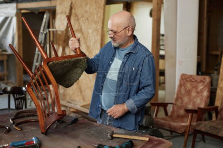 Foto de Retrato de hombre mayor en taller de restauración de muebles fijación de silla de madera vieja, espacio de copia - Imagen libre de derechos