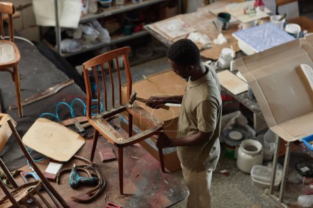 Foto de Retrato de alto ángulo del artesano negro masculino que fija muebles viejos en el taller, espacio de la copia - Imagen libre de derechos