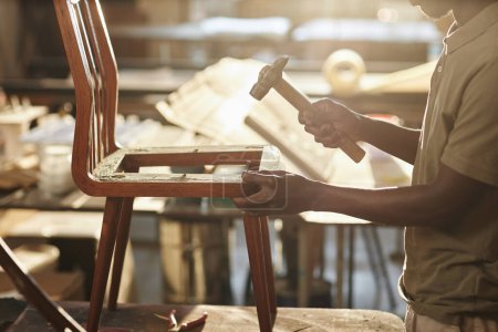 Téléchargez les photos : Gros plan de jeune artisan noir fixant sur les meubles à la lumière du soleil, espace de copie - en image libre de droit