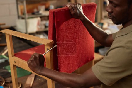 Photo for Closeup of young black man refurbishing old armchair in carpentry workshop, copy space - Royalty Free Image