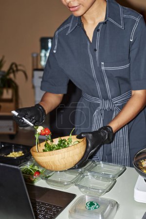 Photo for Vertical closeup of young woman doing healthy meal prep at home and serving salad - Royalty Free Image
