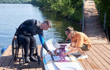 Foto de Retrato completo del hombre con discapacidad listo para ir wakeboarding y montaje de equipo adaptativo con instructor - Imagen libre de derechos