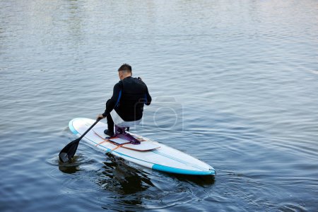 Foto de Retrato mínimo del hombre adulto con discapacidad cabalgando sup board disfrutando de deportes acuáticos al aire libre en la naturaleza, espacio de copia - Imagen libre de derechos