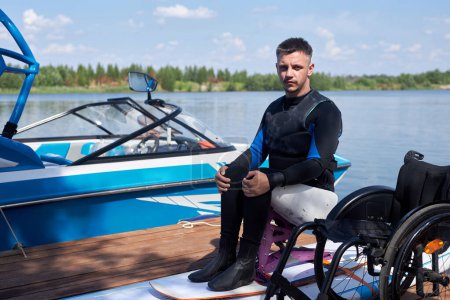 Ganztägiges Porträt eines erwachsenen Mannes mit Behinderung mit adaptiven Sportgeräten im Freien auf einem Pier, Kopierraum