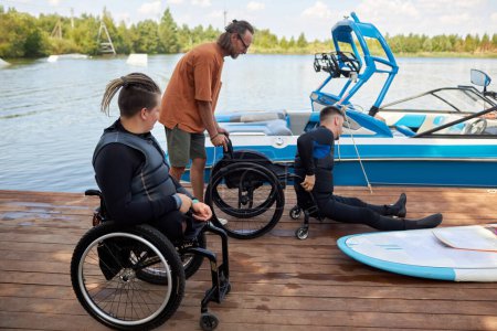 Seitenansicht Porträt von zwei Menschen mit Behinderungen mit adaptiven Sportgeräten auf der Seebrücke, Kopierraum