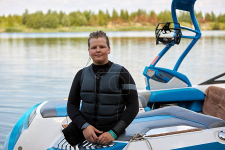 Porträt eines halbwüchsigen Jungen mit Behinderung, der auf einem Boot sitzt und Wassersport im Freien genießt und in die Kamera schaut, Kopierraum