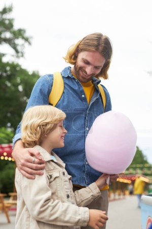 Photo for Side view portrait of happy father buying cotton candy for little boy at amusement park - Royalty Free Image