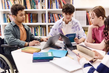 Photo for Inclusive group of students doing homework together sitting at table in school library and holding books - Royalty Free Image