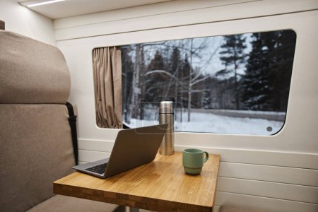 Foto de Primer plano de la computadora portátil abierta en la mesa por las ventanas en el interior de la furgoneta remolque, espacio de copia - Imagen libre de derechos