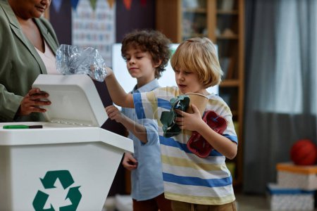 Foto de Retrato de niños clasificando plástico y papel en clase de reciclaje en preescolar, espacio para copiar - Imagen libre de derechos