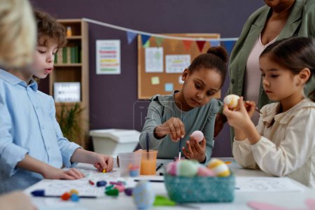 Photo for Diverse group of little children painting Easter eggs at arts and crafts class in preschool - Royalty Free Image
