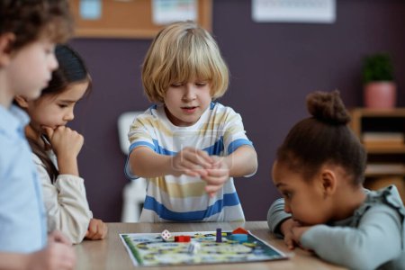 Photo for Diverse group of little kids playing board game together in preschool and throwing dice, copy space - Royalty Free Image