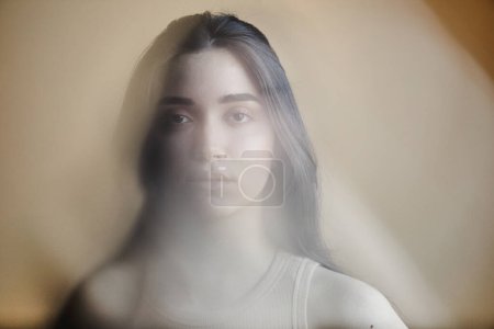 Photo for Blurred portrait of young woman struggling with mental health issues and looking at camera - Royalty Free Image