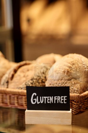 Foto de Primer plano vertical de panes frescos en panadería artesanal con signo sin gluten, espacio para copiar - Imagen libre de derechos