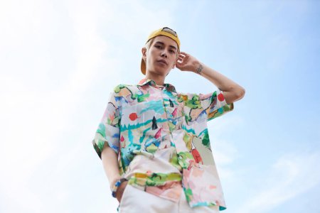 Portrait de mode minime de jeune homme asiatique regardant la caméra portant une tenue à la mode contre un ciel bleu clair, espace de copie