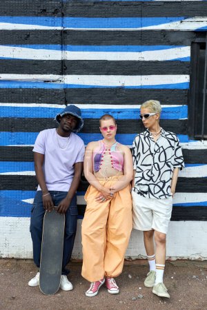 Téléchargez les photos : Portrait complet d'un groupe multiethnique de jeunes portant des tenues à la mode se faisant passer pour un groupe en milieu urbain - en image libre de droit