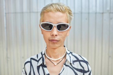 Minimales Porträt eines jungen asiatischen Mannes, der mit Statement-Sonnenbrille vor die Kamera blickt, Kopierraum