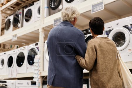 Photo for Back view of senior couple looking at washing machines in household appliances store, copy space - Royalty Free Image