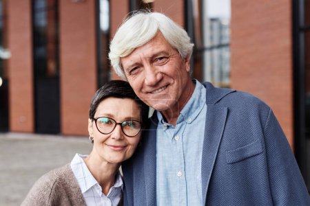 Photo for Portrait of happy senior couple standing outdoors in city and smiling at camera - Royalty Free Image