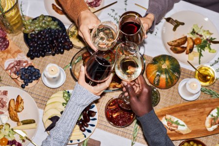 Photo for Top view of people toasting with wine glasses at festive dinner table celebrating Thanksgiving, copy space - Royalty Free Image