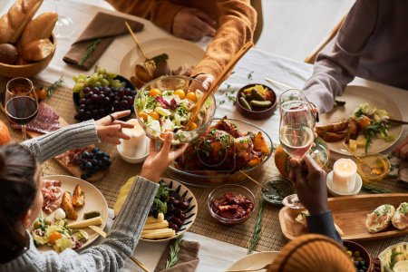 Foto de Grupo multiétnico de personas en la mesa de cena festiva celebrando Acción de Gracias juntos y disfrutando de platos rústicos asados, espacio para copiar - Imagen libre de derechos