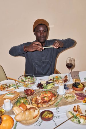 Foto de Retrato vertical del joven negro tomando una foto de la cena de Acción de Gracias con flash - Imagen libre de derechos