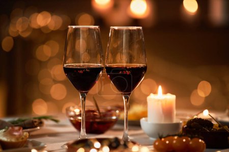 Foto de Primer plano de dos copas de vino en la mesa con luces de Navidad en el fondo, espacio de copia - Imagen libre de derechos