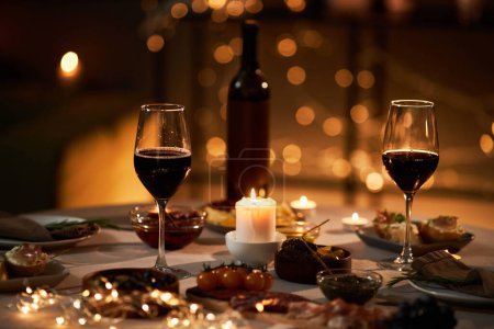 Foto de Imagen de fondo de dos copas de vino en la mesa con luces y velas de Navidad, espacio para copiar - Imagen libre de derechos