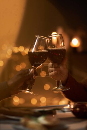 Photo for Close up of two people toasting with wine glasses at romantic dinner table during date, copy space - Royalty Free Image