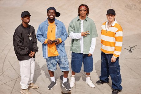 Gruppe von vier jungen interkulturellen Mitgliedern einer Boyband in trendiger Freizeitkleidung blickt im urbanen Umfeld in die Kamera